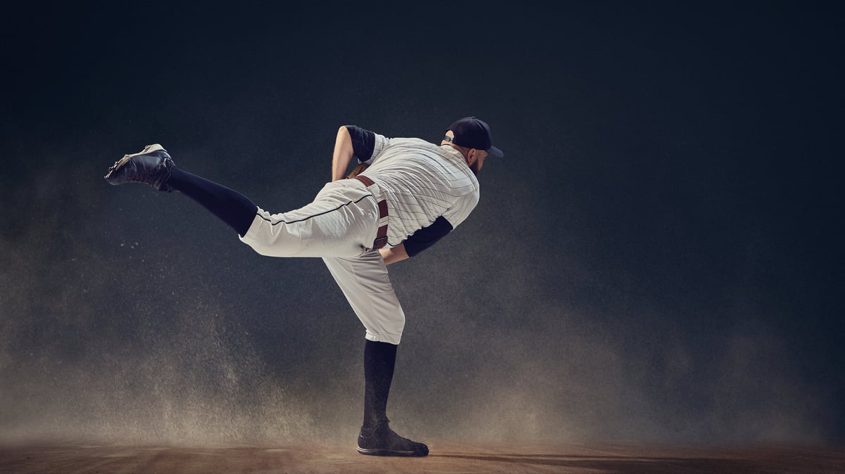 Baseball pitcher completing throw follow-through with dust swirling